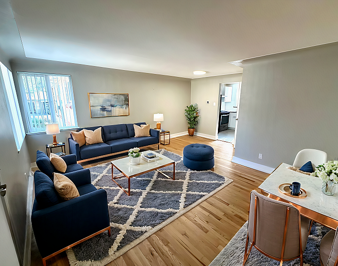 Bright and inviting living room with modern navy sofas and elegant decor, complemented by natural light and a stylish dining area.