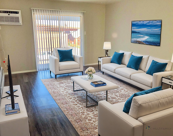 Bright and modern living room with elegant white sofas, blue accent pillows, and stylish decor, showcasing a serene and inviting atmosphere.
