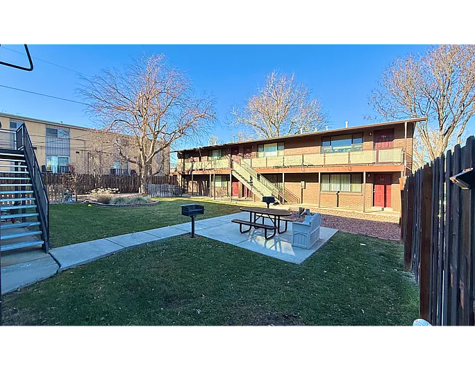 Charming brick apartment complex with spacious courtyard, picnic area, and built-in barbecue grill, ideal for outdoor living.