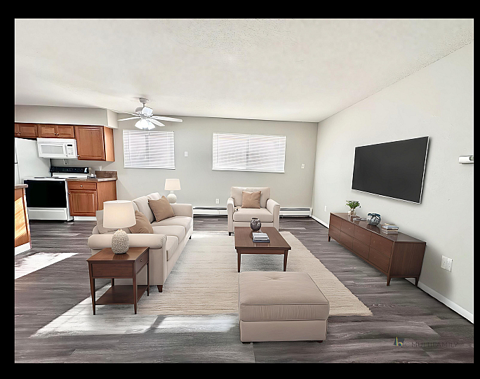 Modern open-concept living room with elegant furnishing, hardwood floors, and a stylish kitchen in the background.