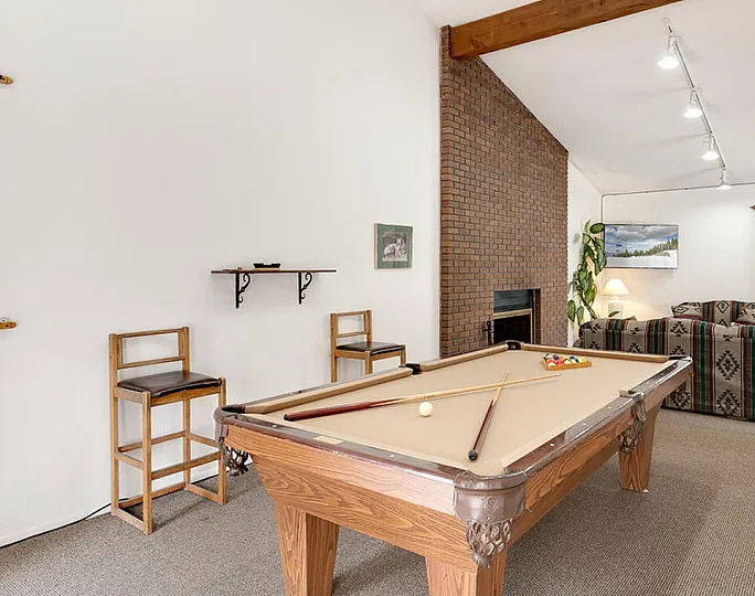 Inviting living space with a cozy pool table and rustic brick fireplace, perfect for entertainment and relaxation.