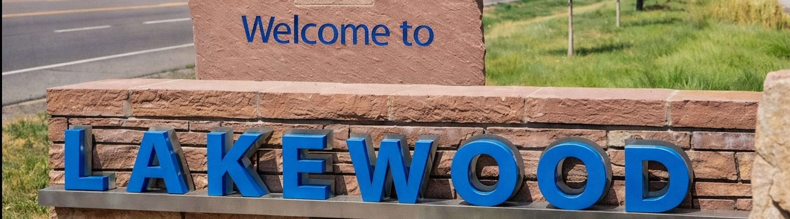 Inviting entrance sign to Lakewood against a backdrop of trees and a vibrant blue sky.