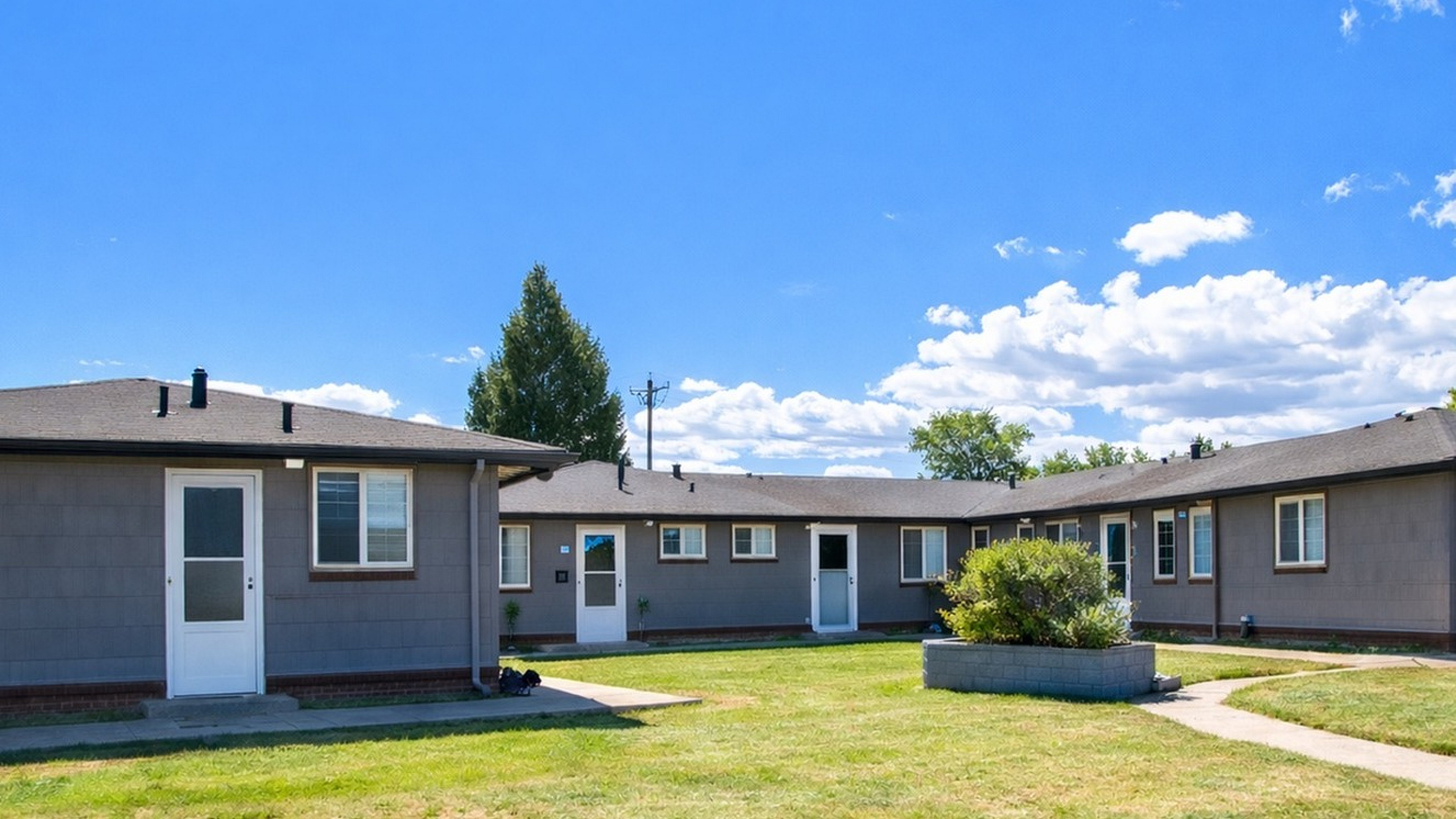 Charming single-story apartments with private entrances, nestled in a serene setting with a well-kept lawn, ideal for relaxed living.