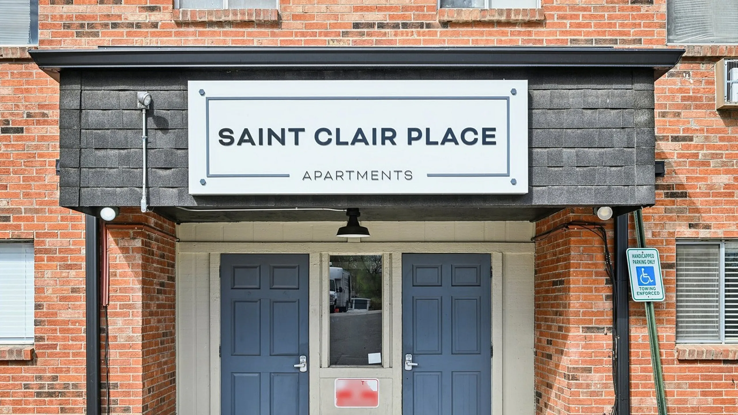 Charming apartment entrance with red brick facade and classic double doors at Saint Clair Place.