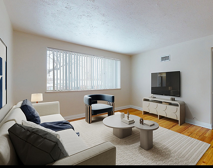 Inviting living room with elegant hardwood floors, modern furnishings, and abundant natural light through large window blinds.