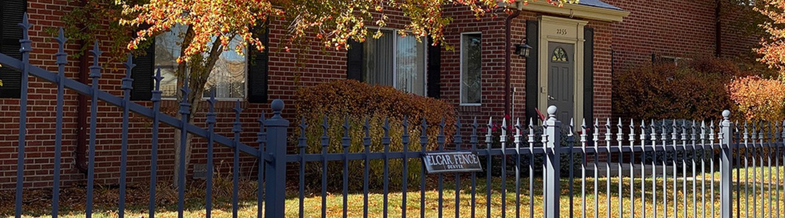 Charming brick apartment building with lush autumn foliage and a welcoming entrance, perfect for cozy living.