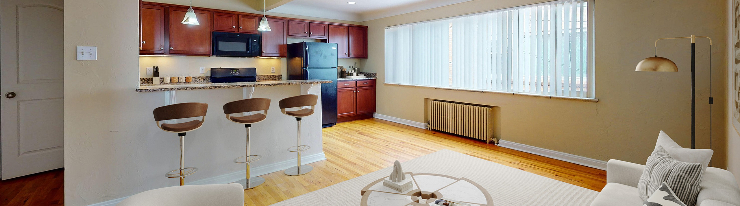Bright and inviting apartment with open-plan living room and modern kitchen featuring elegant bar seating, large windows, and cozy furnishings.