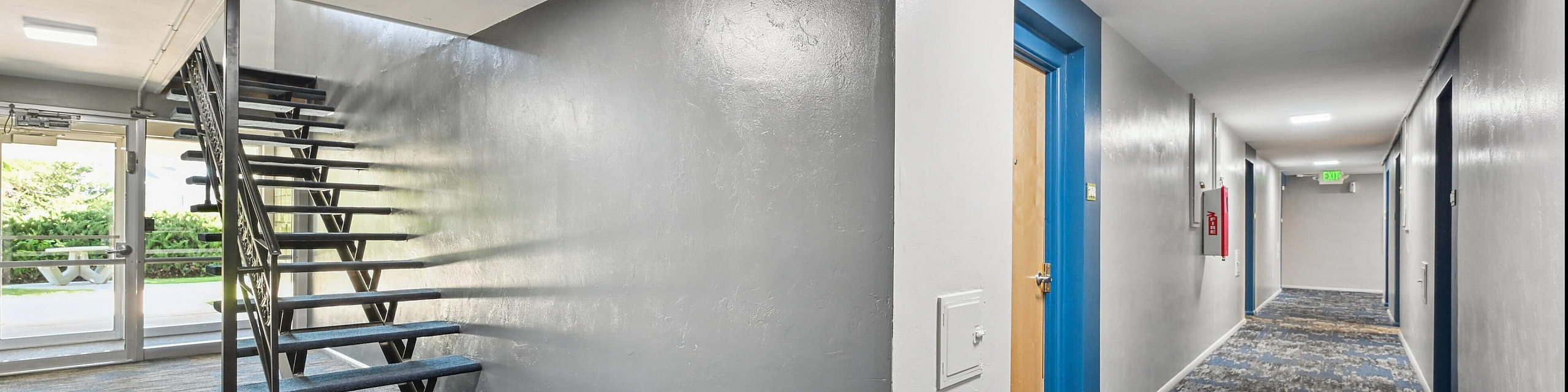 Bright modern apartment hallway with stylish carpeting and sleek staircase leading to an inviting entrance.