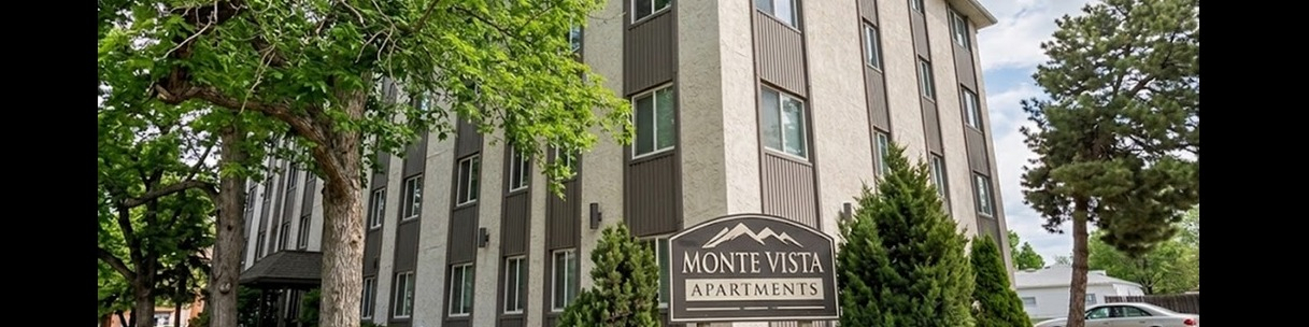 Charming Monte Vista Apartments surrounded by lush greenery, featuring a modern four-story building with ample natural light.