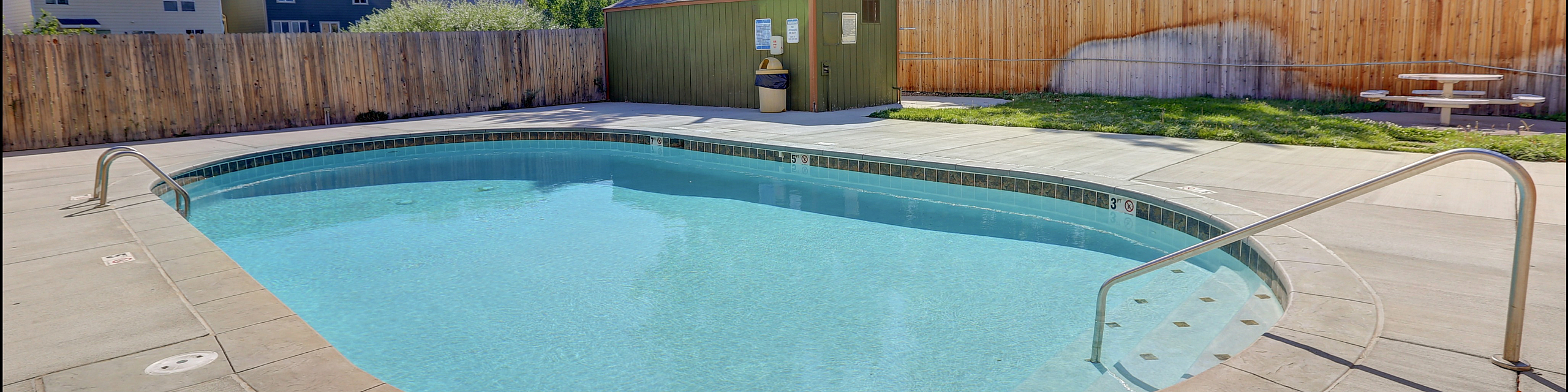 Inviting outdoor pool area with crystal clear water, perfect for relaxation and enjoyment, surrounded by well-maintained greenery and privacy fencing.
