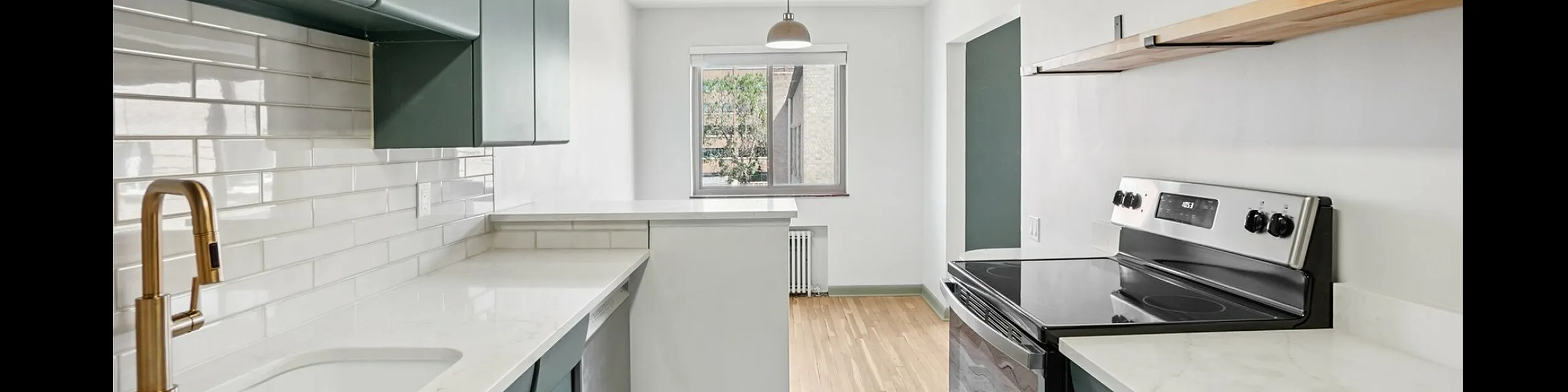 Bright, modern kitchen with sleek cabinetry, marble countertops, and a stainless steel stove, complemented by a large window and stylish lighting.
