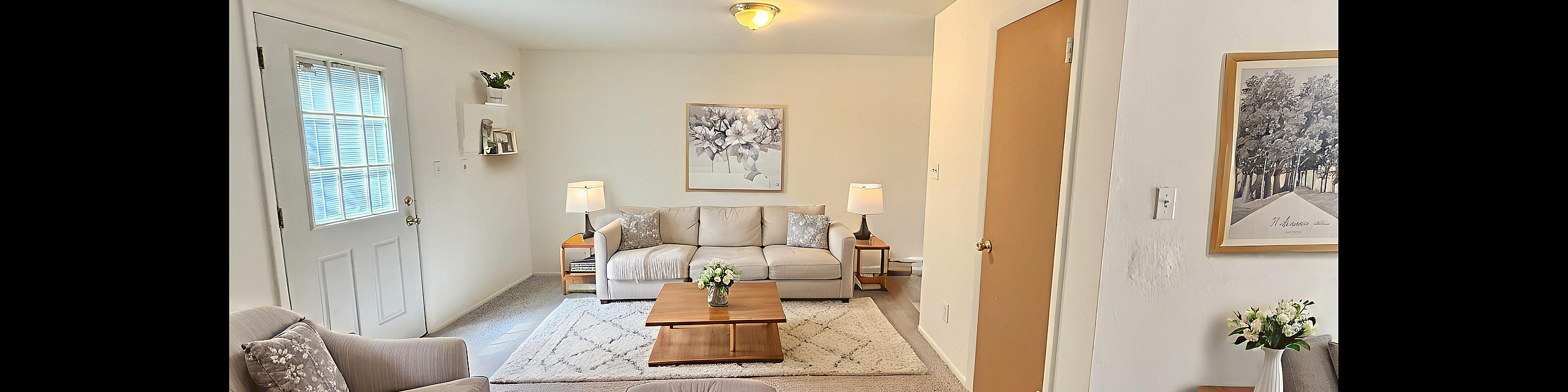 Bright and welcoming living room featuring elegant neutral d&eacute;cor, plush seating, and tasteful floral accents.