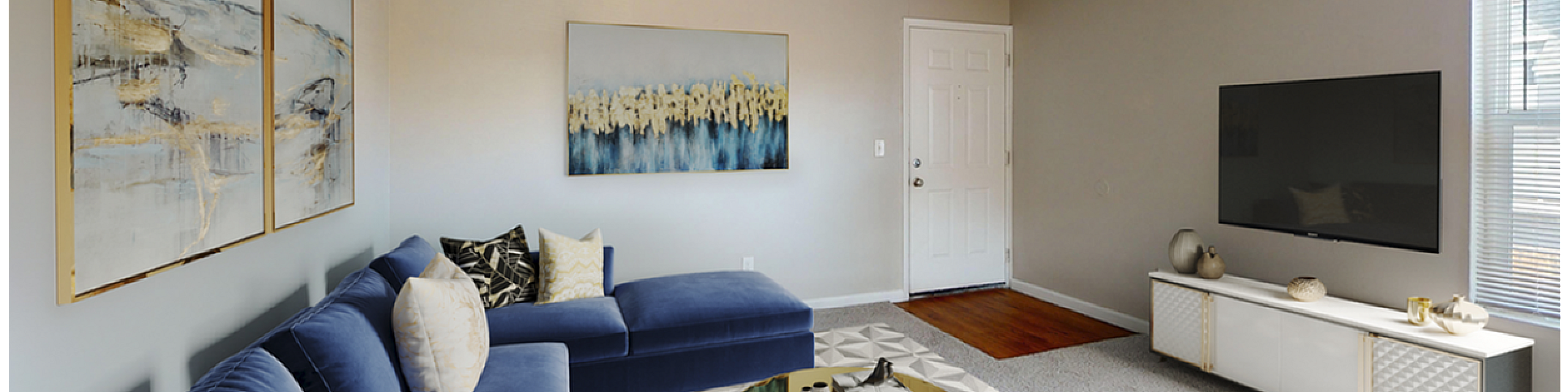 Elegant living room with plush blue sectional sofa, abstract wall art, and a chic round coffee table. Bright and airy space with modern TV console and natural light streaming through large windows.
