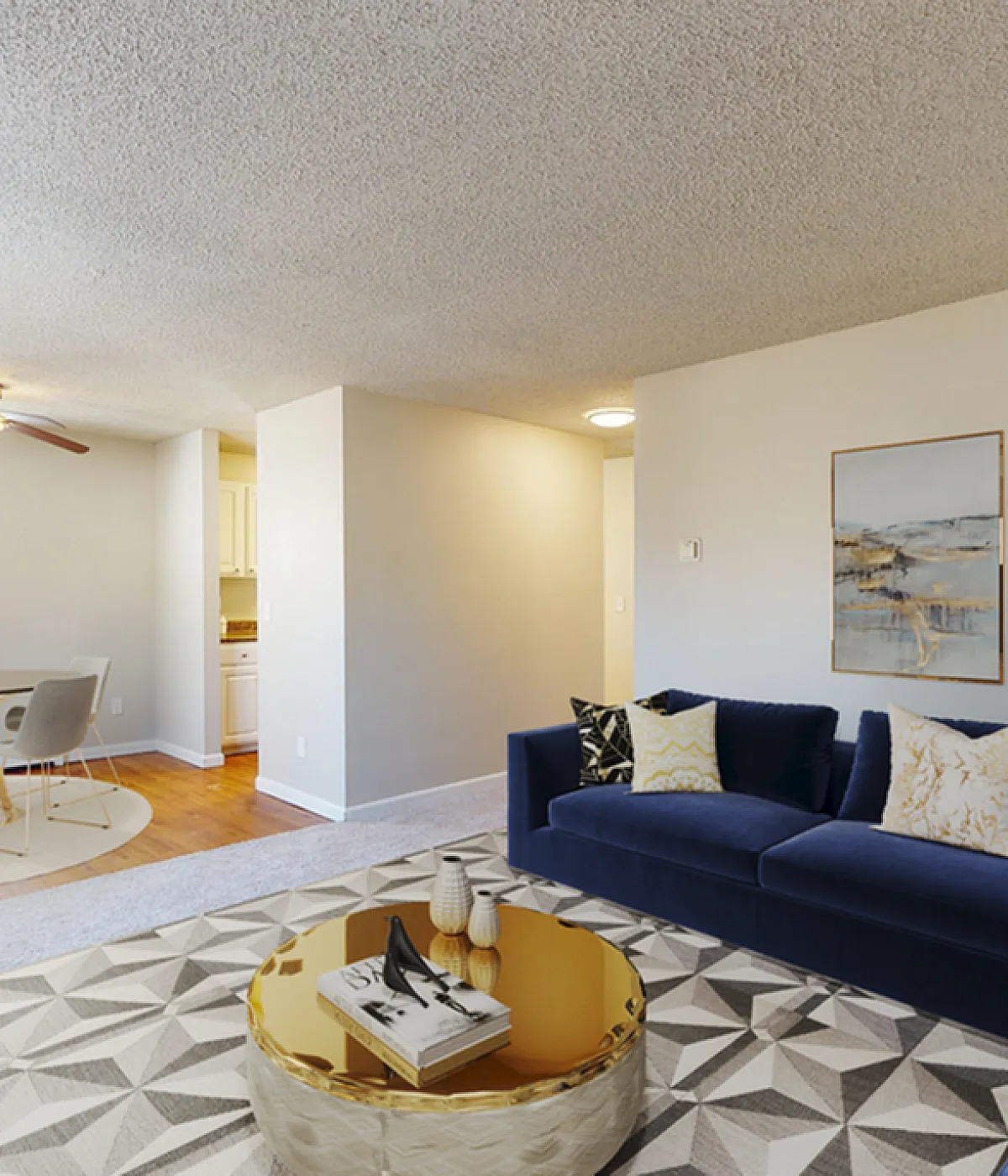 Elegant living area with plush navy sofa, geometric rug, and chic dining space, featuring modern decor and warm natural light.