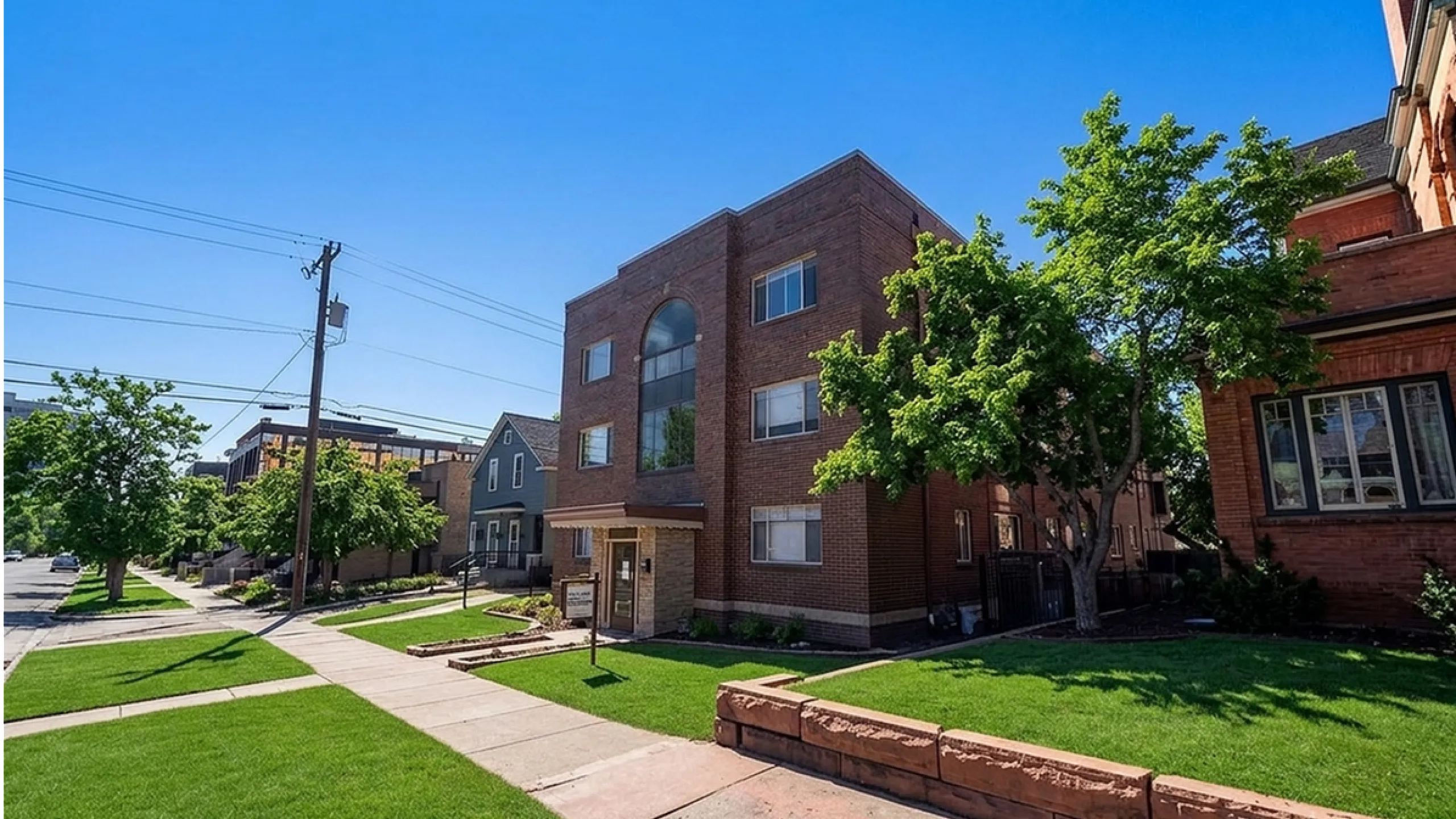 Charming brick apartment building with lush green lawns, nestled in a serene neighborhood setting, perfect for urban living.