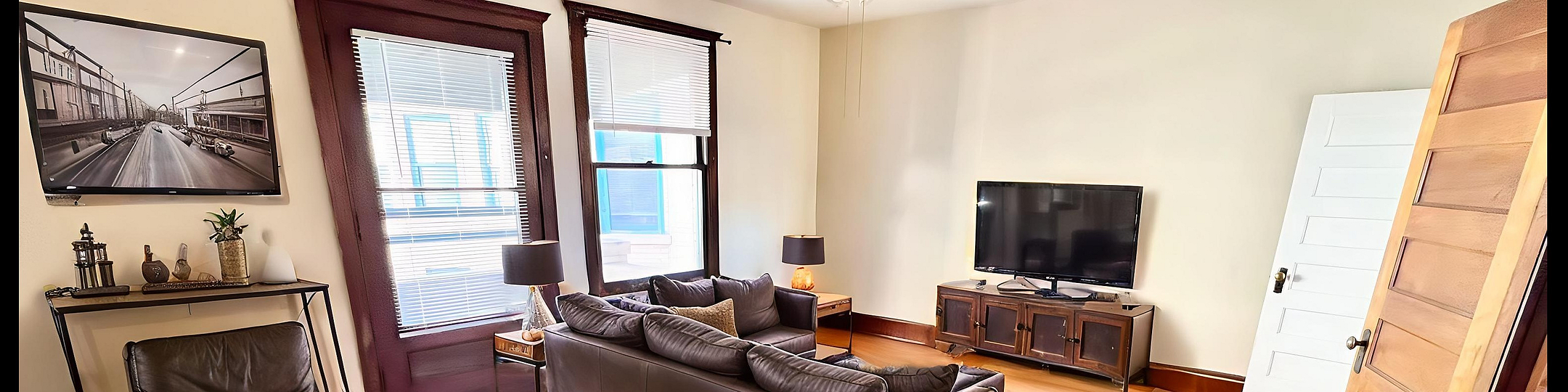 Inviting living room with elegant leather seating, stylish wooden furniture, and abundant natural light through large windows.