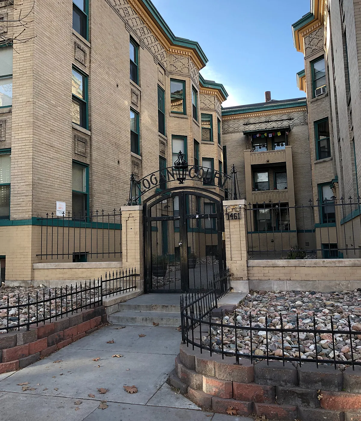 Charming apartment building with classic brick architecture, elegant iron gate entrance, and inviting stone pathways.