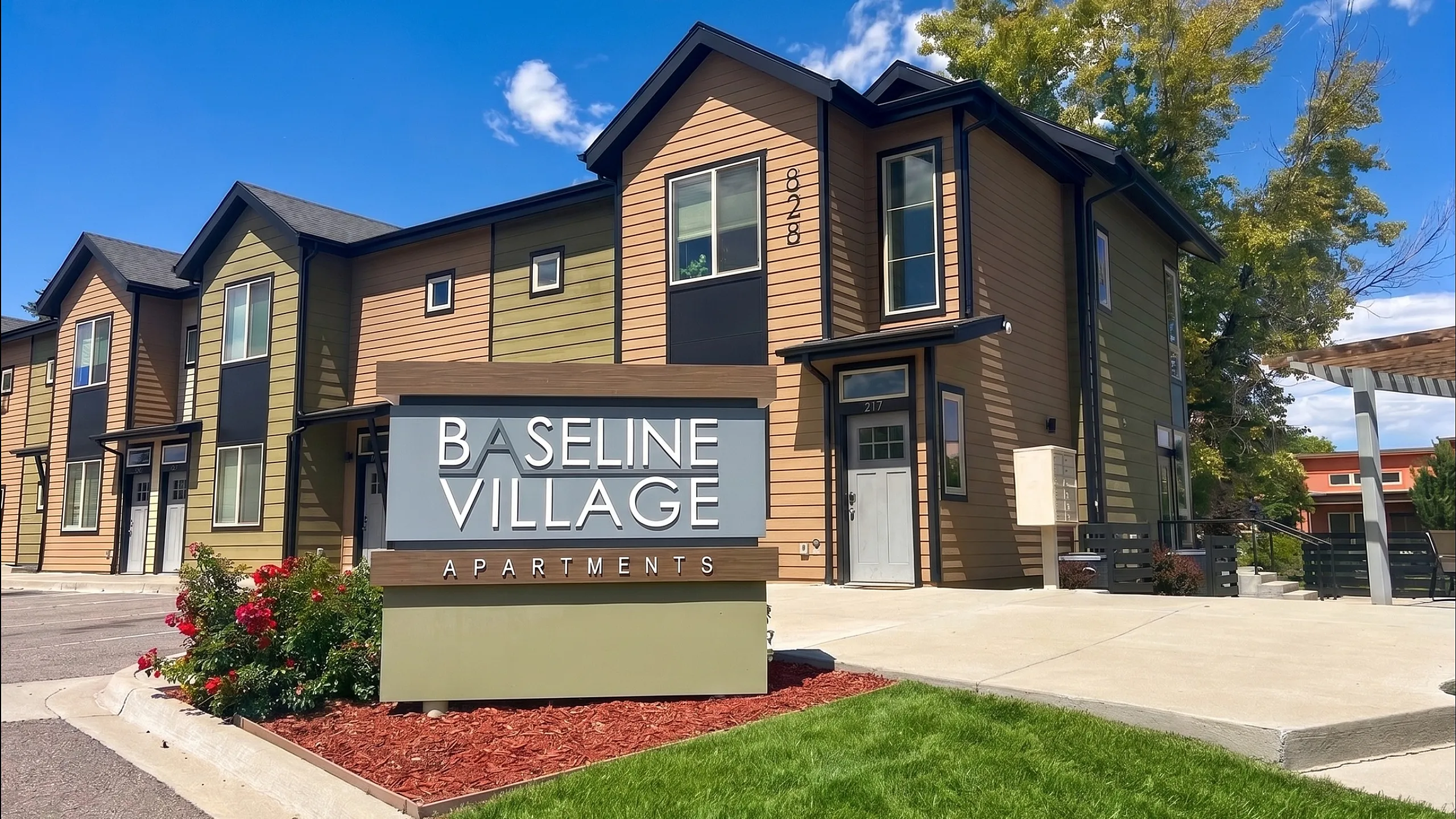 Charming Baseline Village Apartments showcasing modern architecture, lush landscaping, and a vibrant community atmosphere under a clear blue sky.