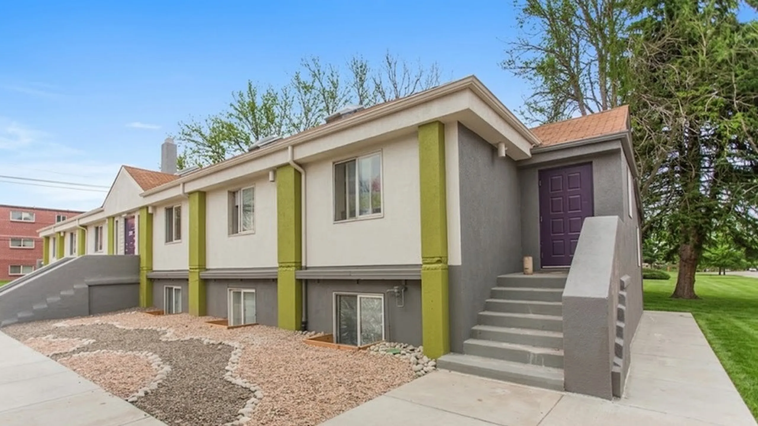 Charming modern apartment exterior with vibrant accents and lush greenery, showcasing inviting pathways and a beautifully maintained facade.