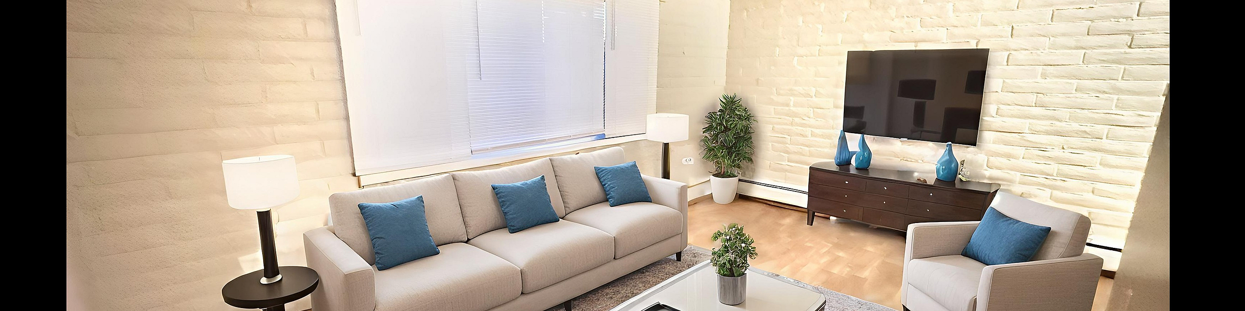 Bright living room with contemporary decor featuring a cozy sofa, elegant armchairs, and a sleek TV unit. Soft lighting and a plush rug create a welcoming ambiance.