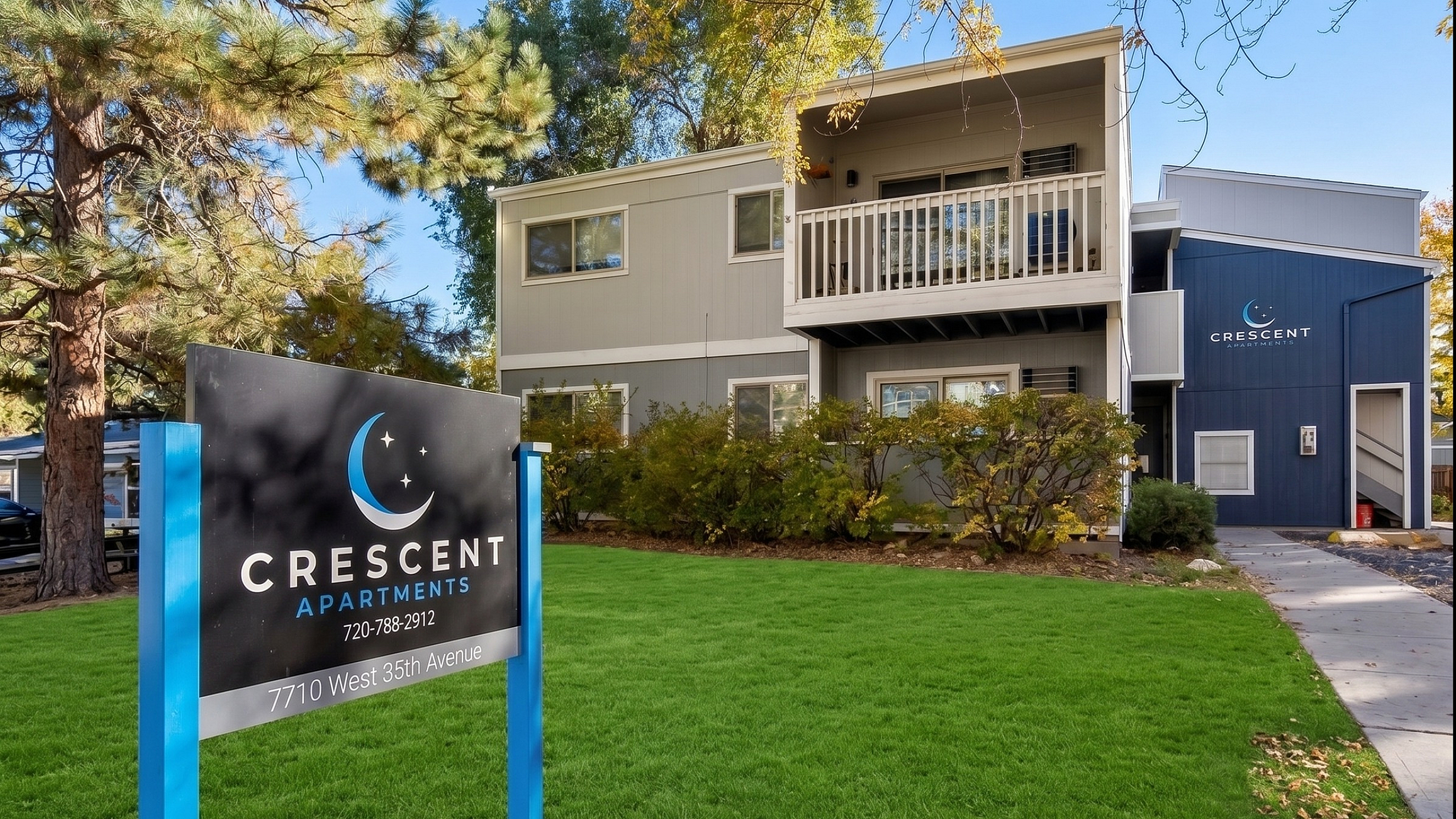 Elegant Crescent Apartments exterior featuring lush green lawns and modern architecture set against a backdrop of tall trees.