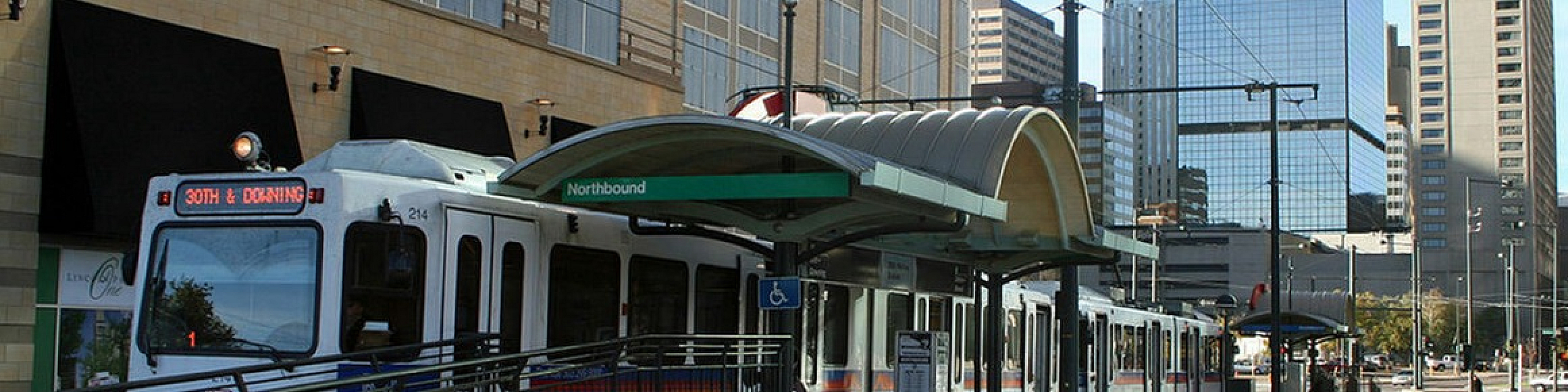 Modern urban scene featuring a well-connected light rail stop near sleek high-rise apartments, just a 2-minute walk to 20th & Welton.