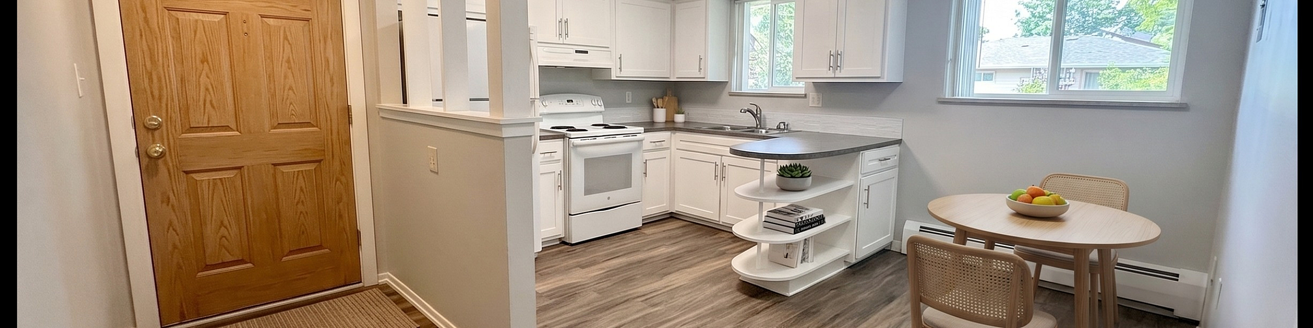 Charming open-layout kitchen with sleek white cabinets, wood flooring, and cozy dining area by a bright window.