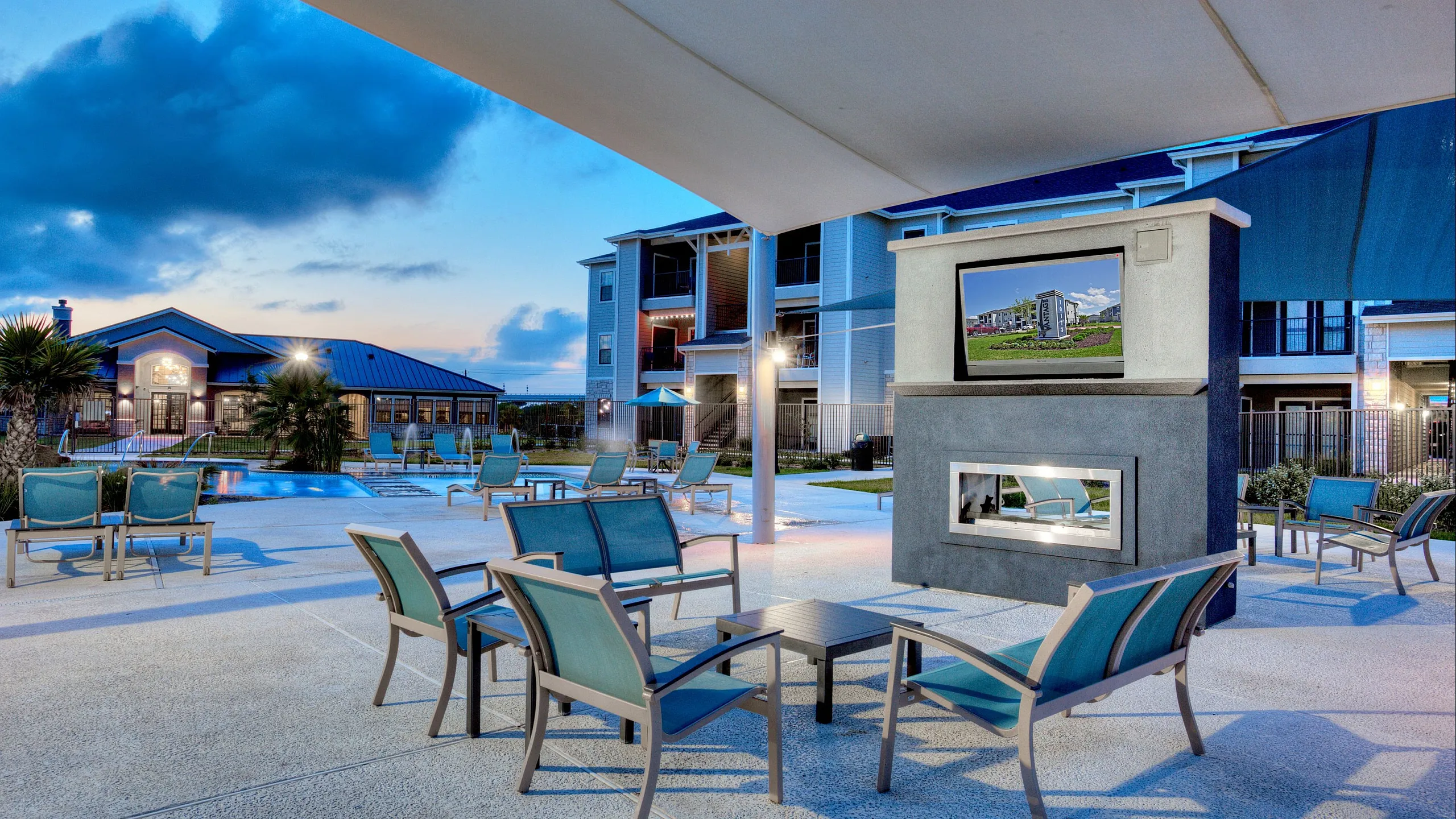 Luxurious outdoor patio with cozy seating, a built-in TV, and stunning pool view, perfect for evening relaxation.