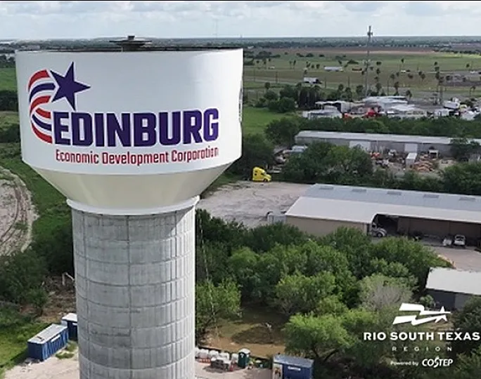 Panoramic aerial view showcasing the vibrant Edinburg water tower surrounded by lush greenery and open land, highlighting the potential for thriving development in the Rio South Texas region.