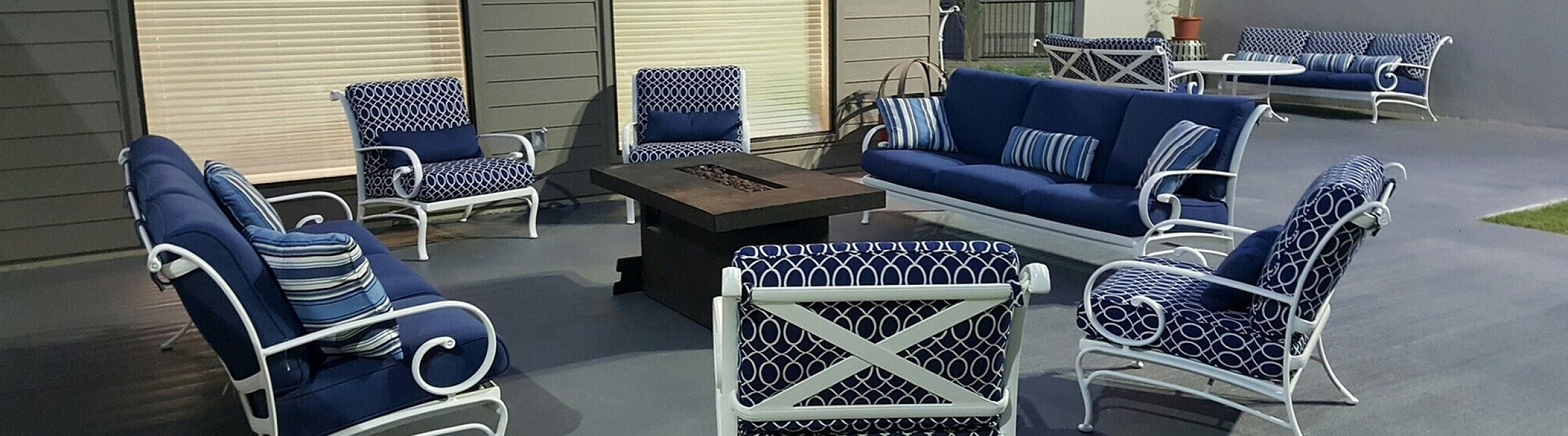 Elegant outdoor seating area featuring stylish blue cushioned chairs and a cozy fire pit table, perfect for entertaining in a sophisticated setting.