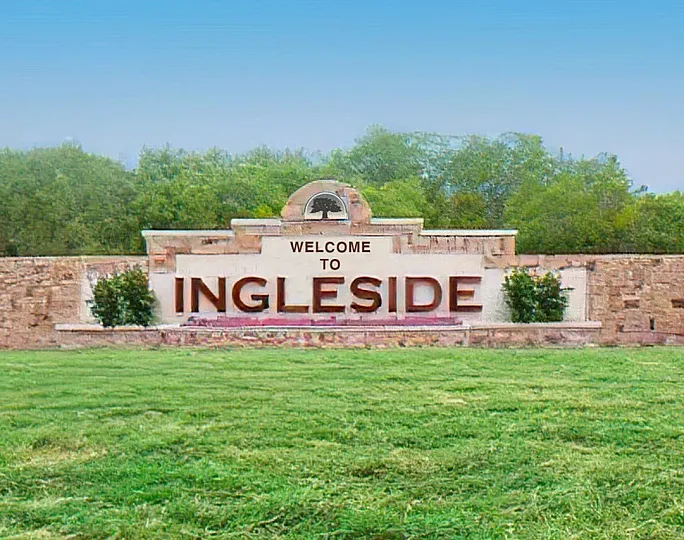 Charming entrance sign warmly welcomes you to Ingleside, surrounded by lush greenery and a serene backdrop.