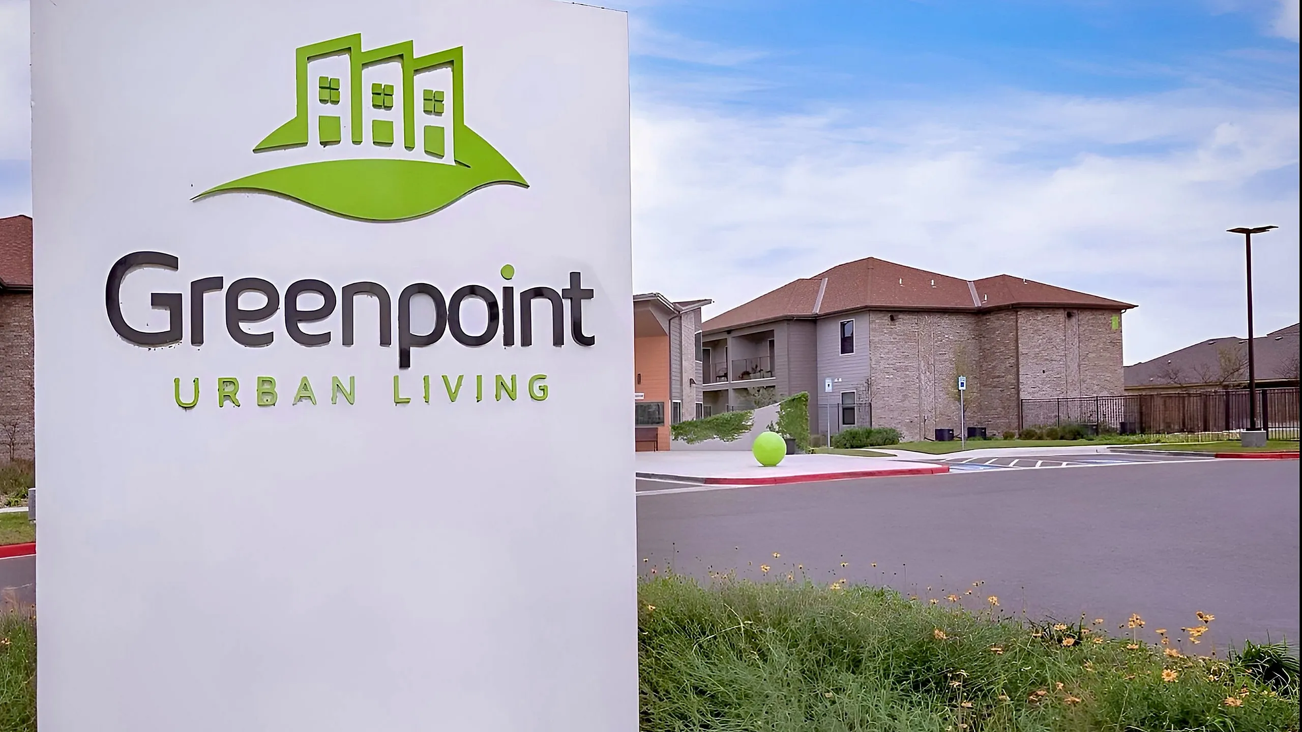 Charming urban living complex with modern design at Greenpoint, surrounded by lush greenery and bright skies.