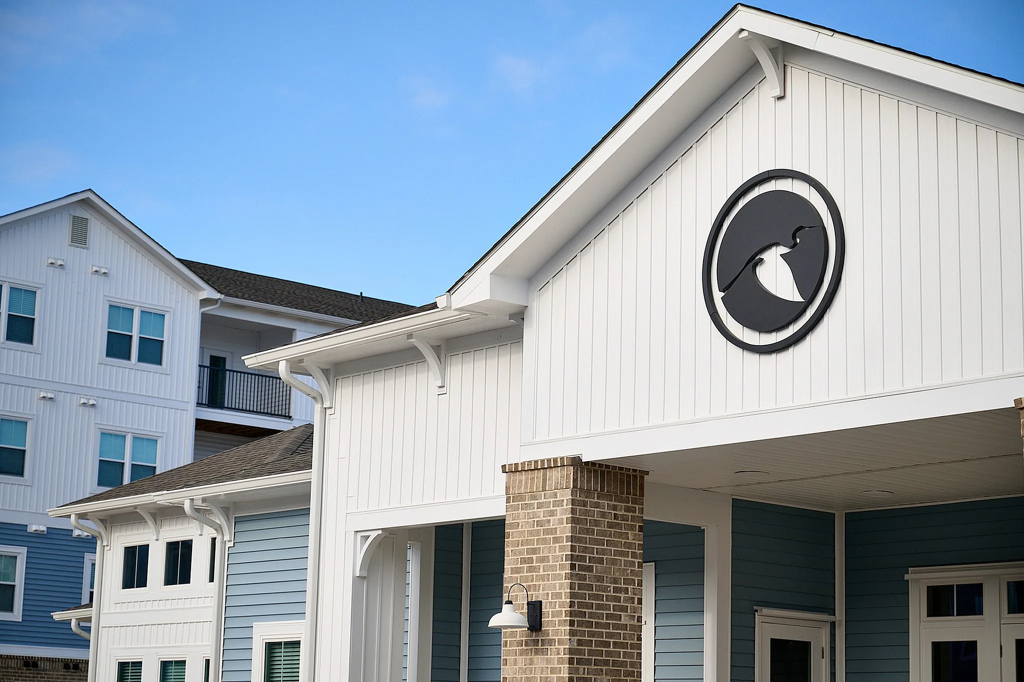 Elegant exterior of modern apartment complex with blue and white siding, showcasing architectural design and a serene atmosphere.