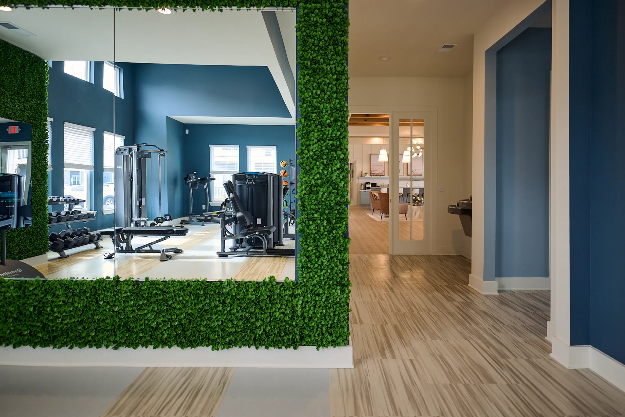 Bright gym with modern equipment and welcoming living room in elegant apartment complex.