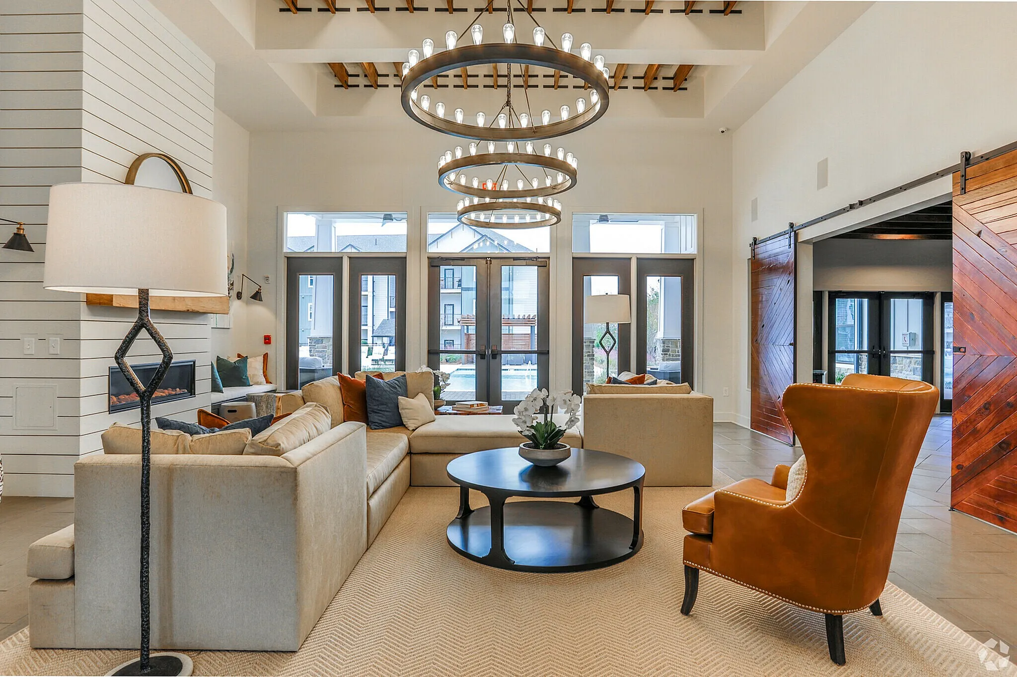 Spacious living room with modern design, featuring a cozy sofa, elegant chandelier, and warm lighting.