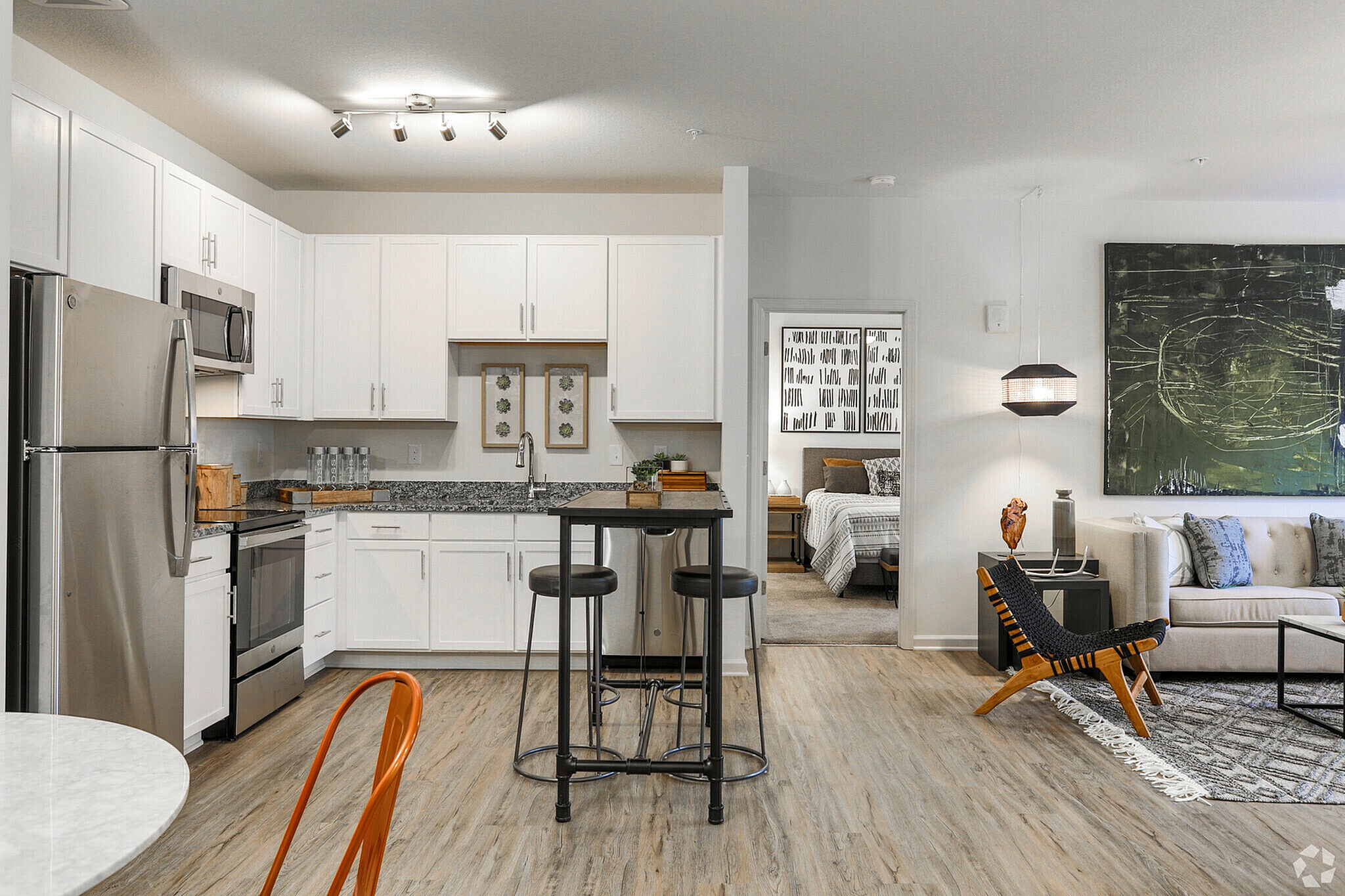 Modern kitchen and living area with stylish decor and cozy bedroom in the background.