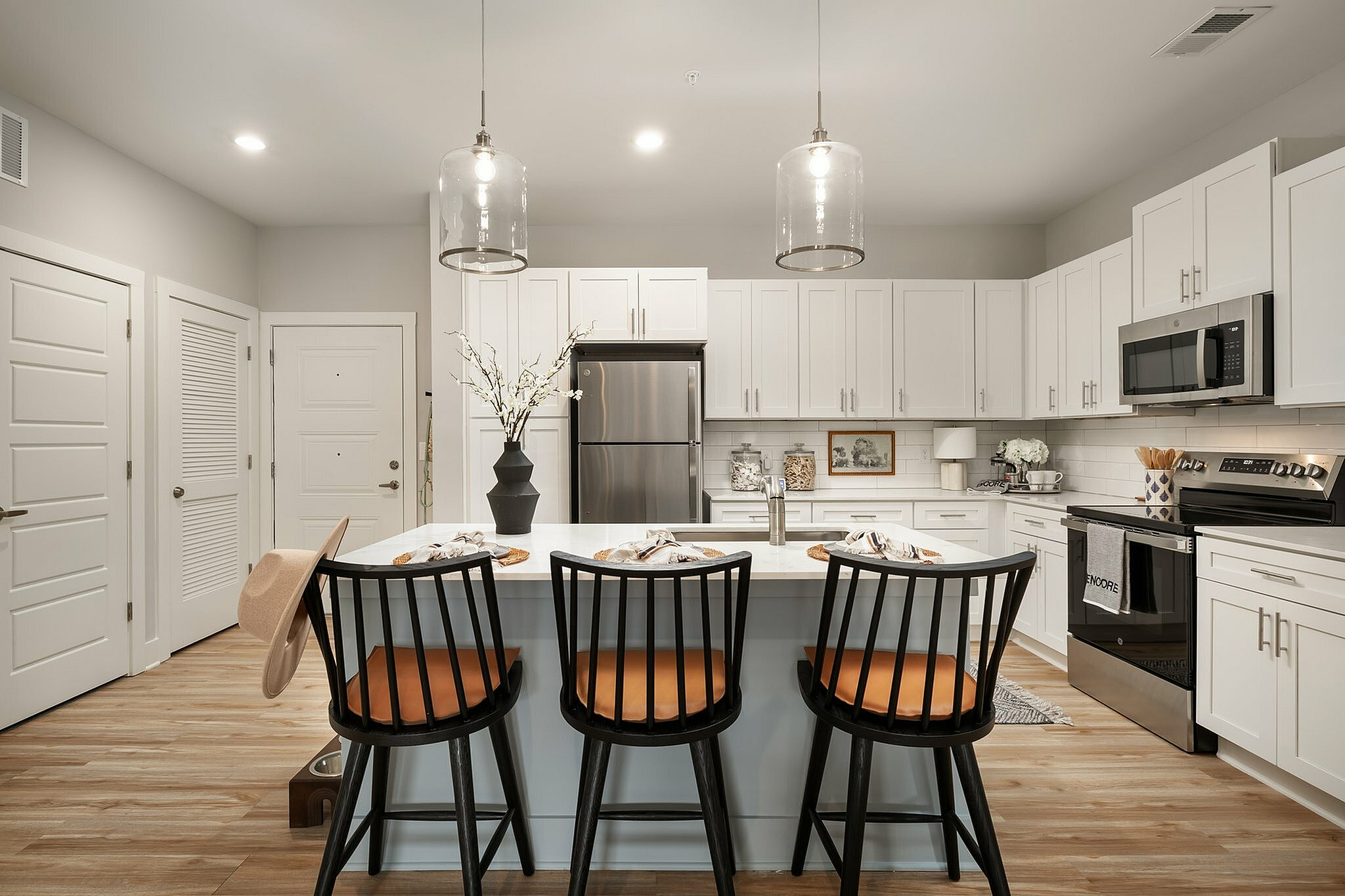 Inviting modern kitchen with white cabinets, stainless steel appliances, and a stylish island with seating.