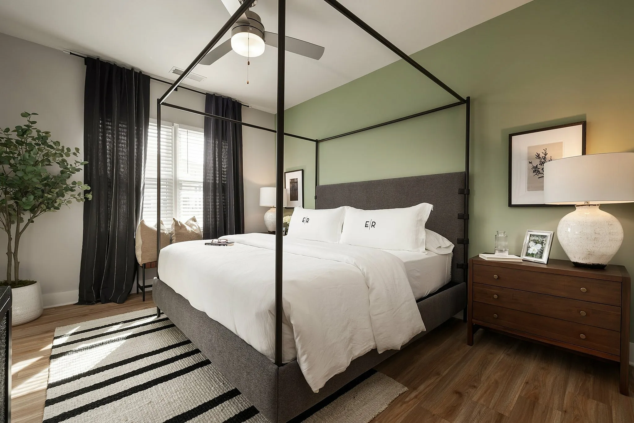 Luxurious bedroom with a canopy bed, green accent wall, and stylish decor.