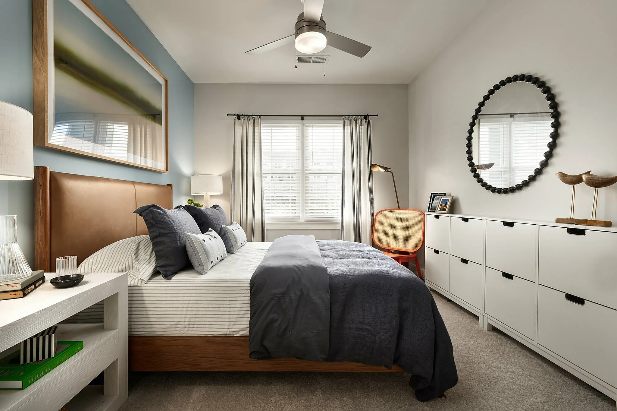 Cozy bedroom with stylish decor, featuring a plush bed, artistic wall decor, and ample natural light.