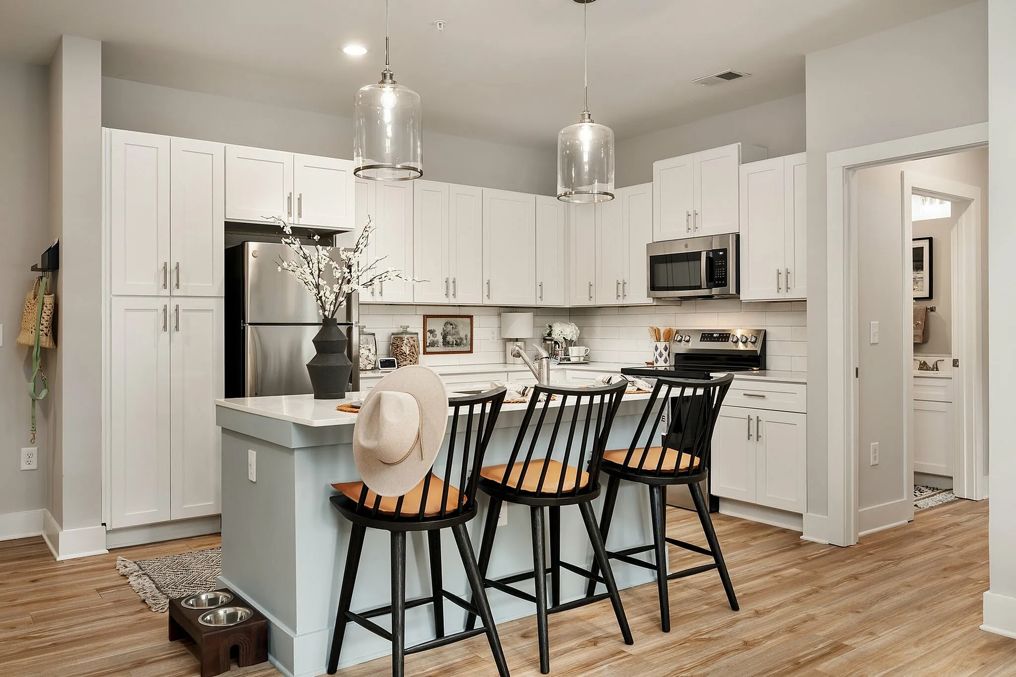 Bright modern kitchen with white cabinetry, stainless steel appliances, and a central island with bar stools.
