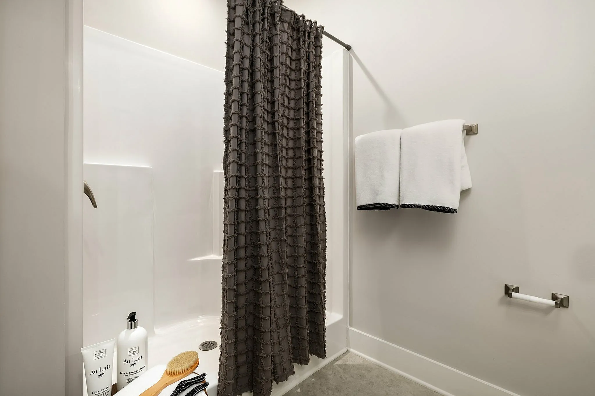Inviting bathroom with a stylish shower, textured curtain, and fresh white towels.