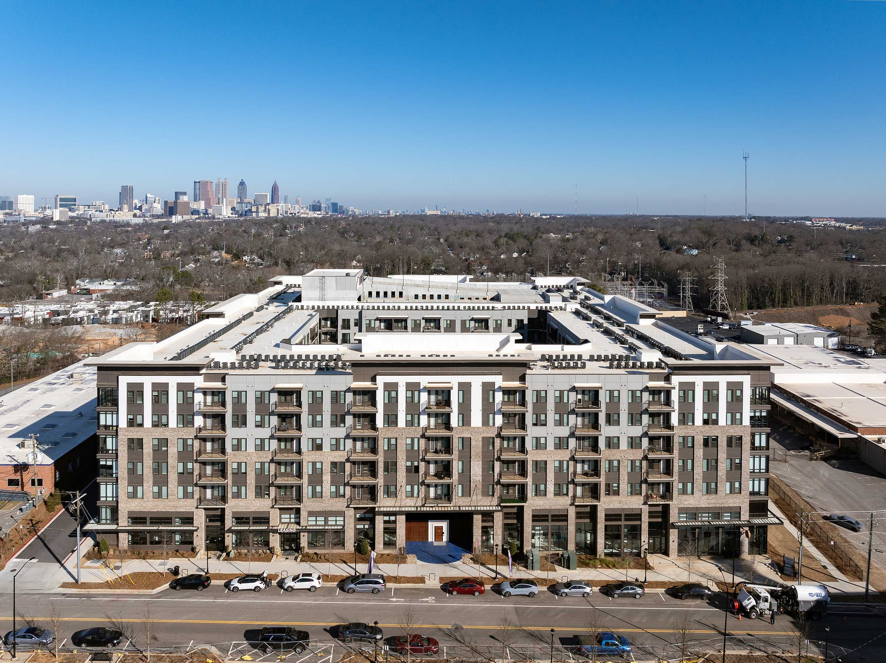 Contemporary urban apartment complex with stunning city skyline backdrop, offering luxurious living spaces and modern amenities.