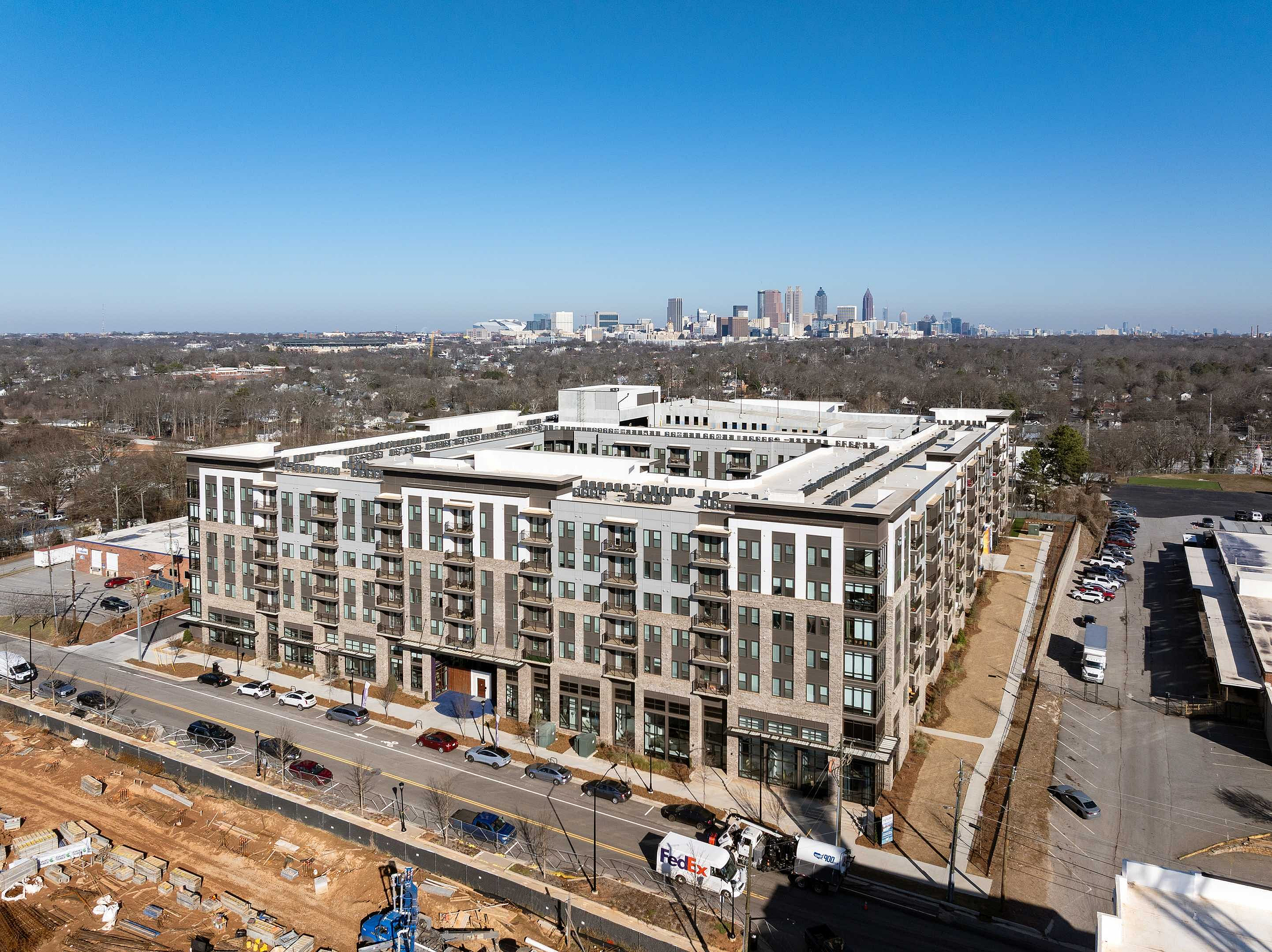 Modern urban apartment complex with a stunning cityscape backdrop, featuring ample balconies and contemporary architecture.