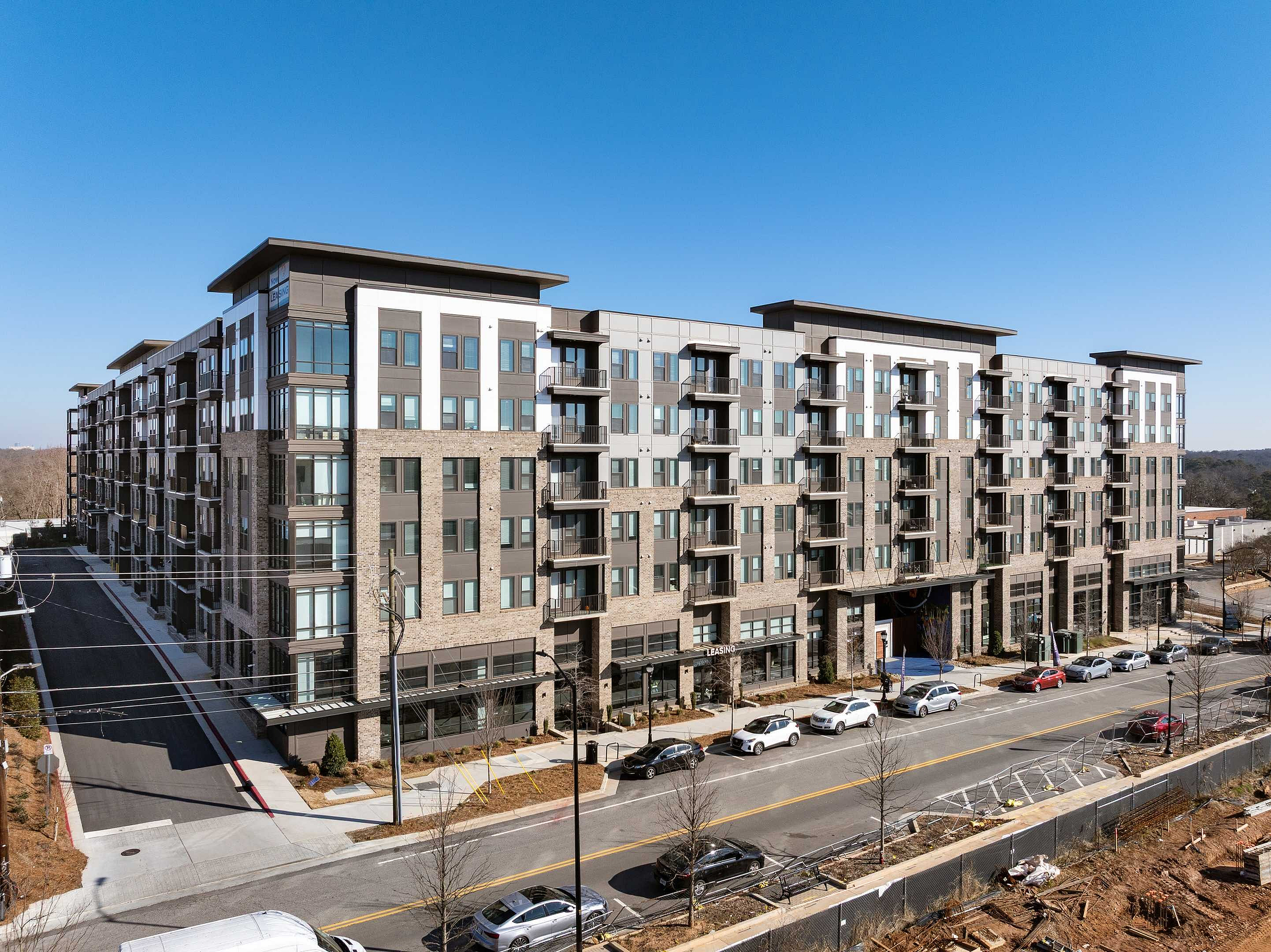 Modern apartment complex with sleek design, large windows, and balconies, situated in a vibrant urban setting.