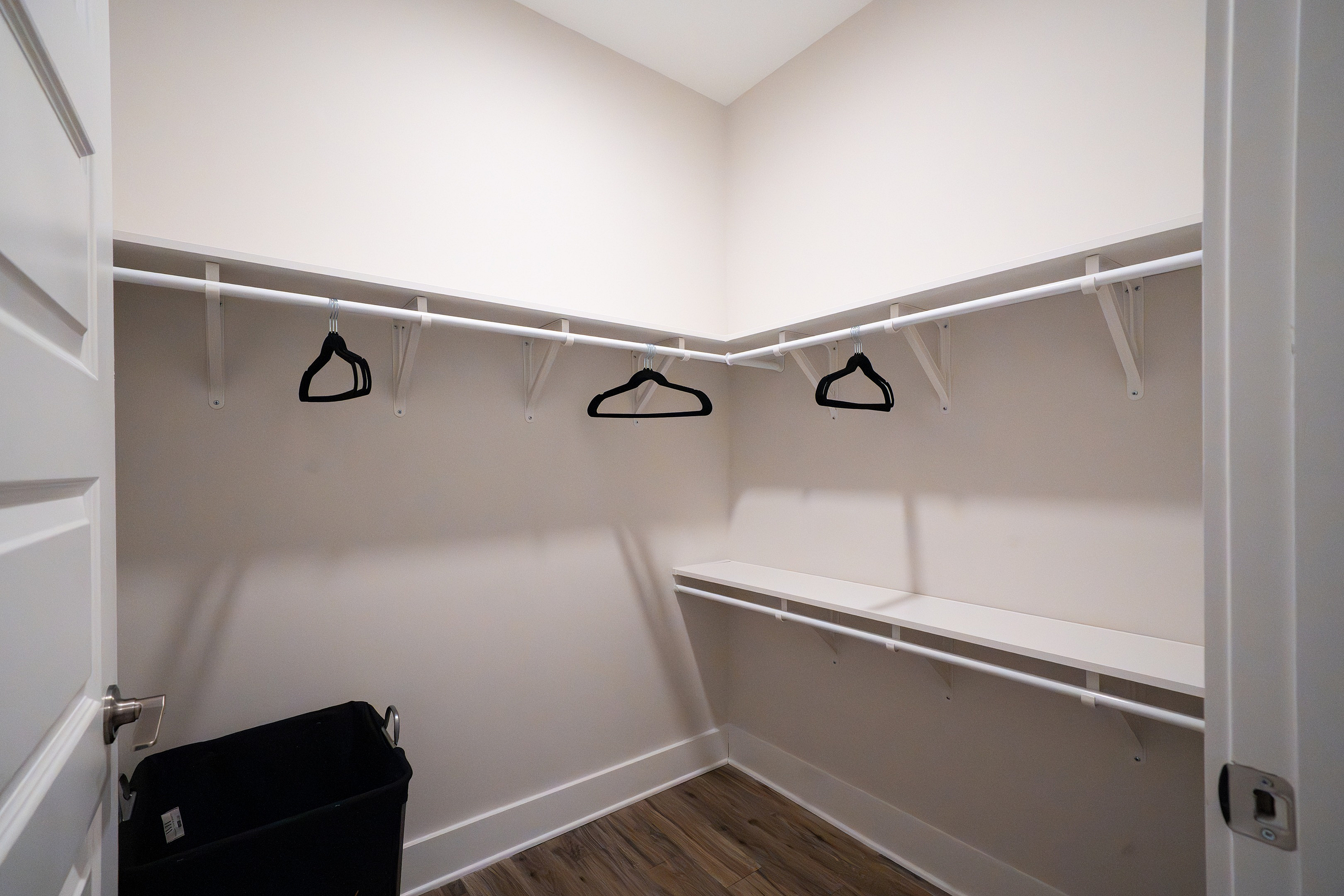 Spacious walk-in closet with sleek design, featuring ample shelving and hanging space on polished hardwood floors.