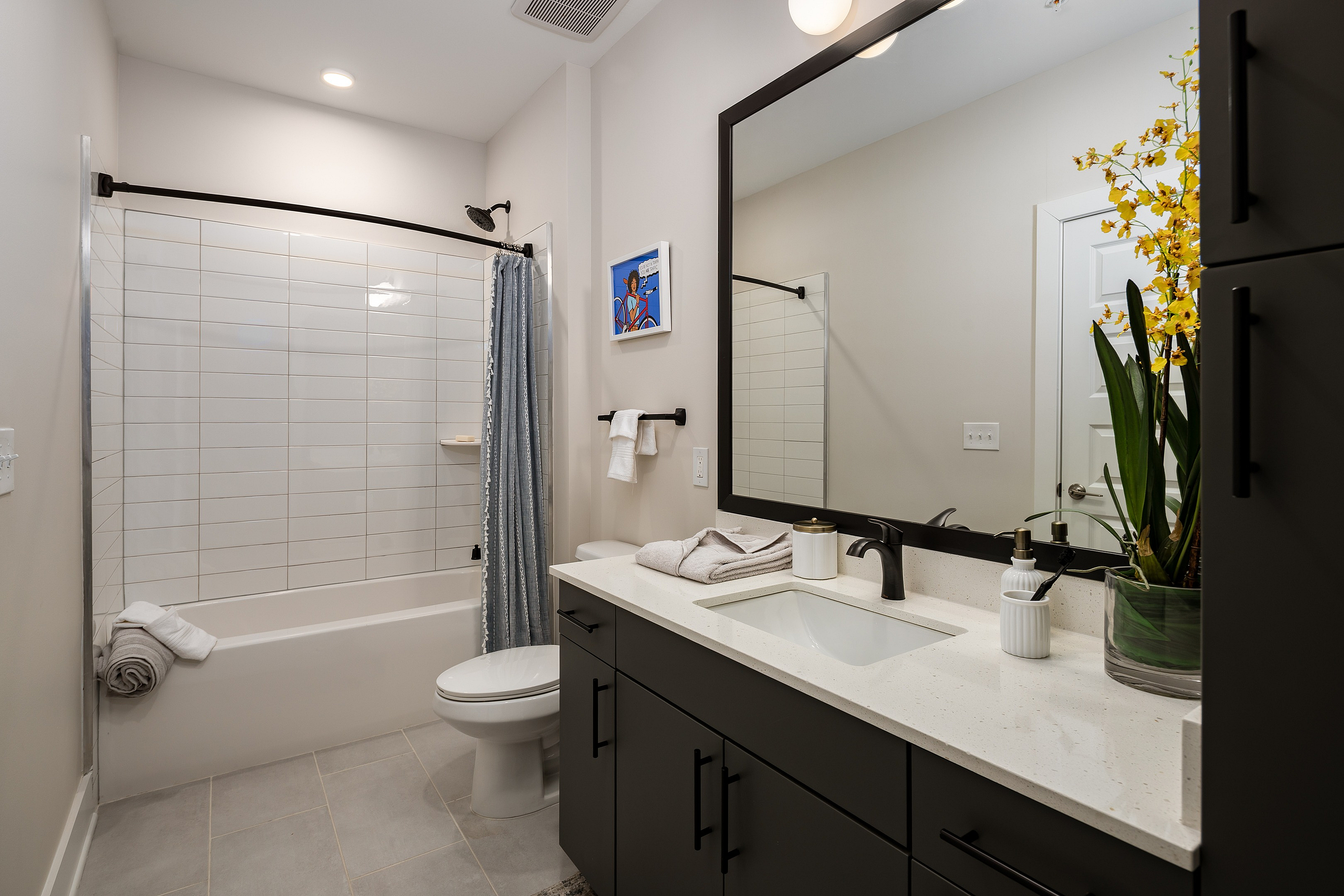 Elegant bathroom featuring modern fixtures, a spacious vanity, and luxurious shower with tiled walls, complemented by stylish decor and vibrant accent plant.
