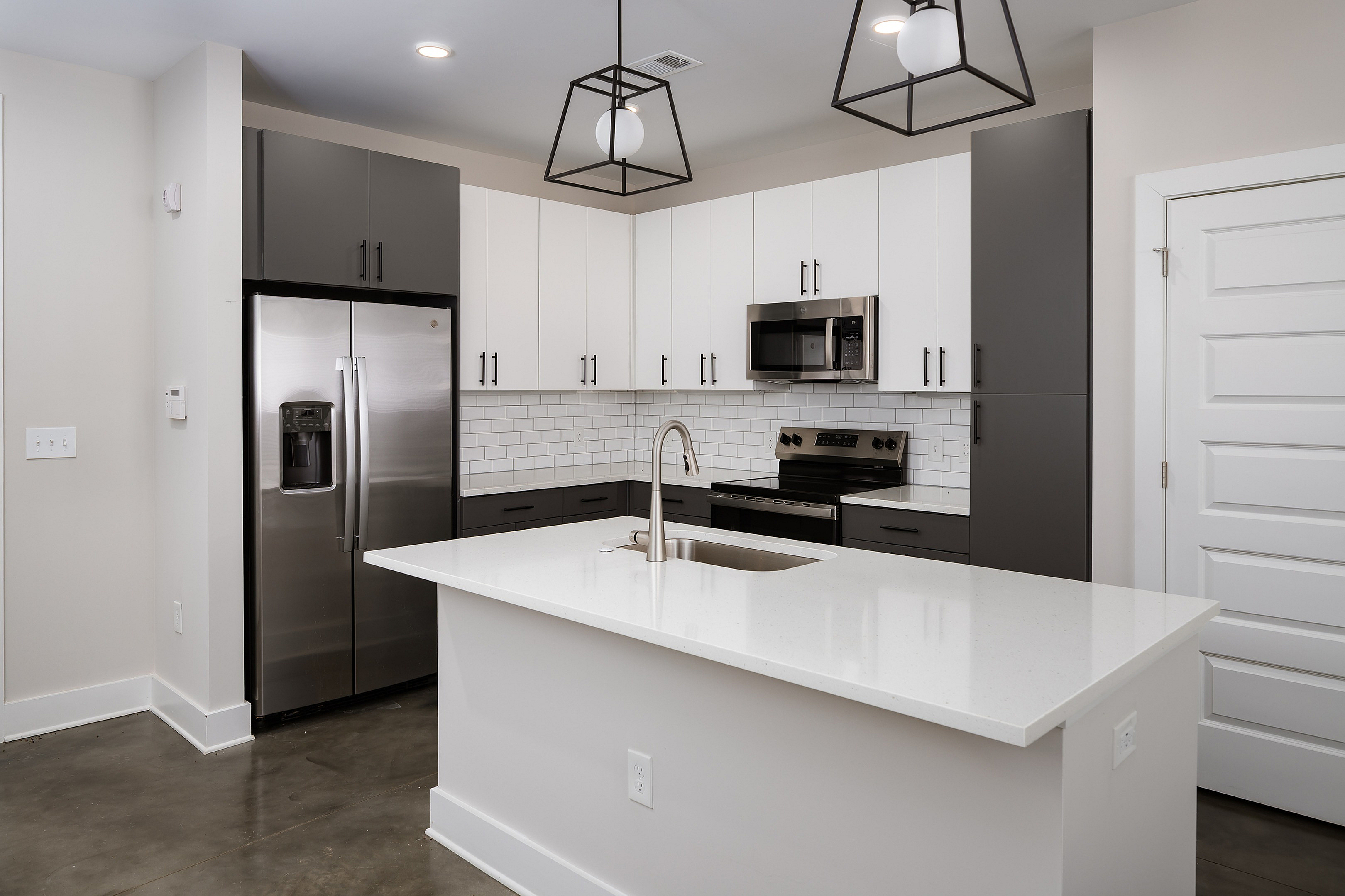 Modern kitchen with sleek stainless steel appliances, elegant black and white cabinetry, and a spacious island with a built-in sink.