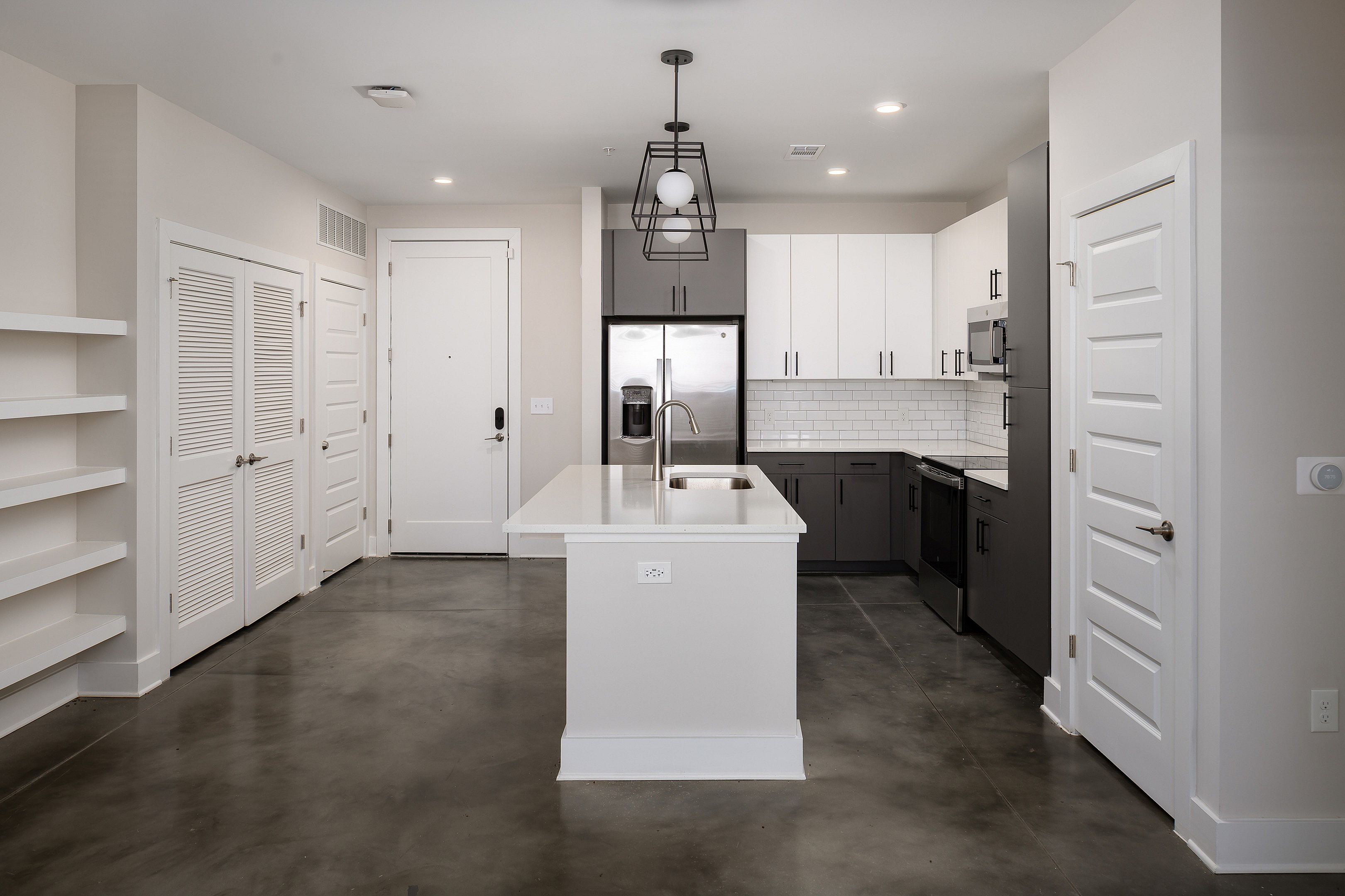 Sleek modern kitchen with elegant white cabinetry, stainless steel appliances, and a chic pendant light enhancing the open-concept space.