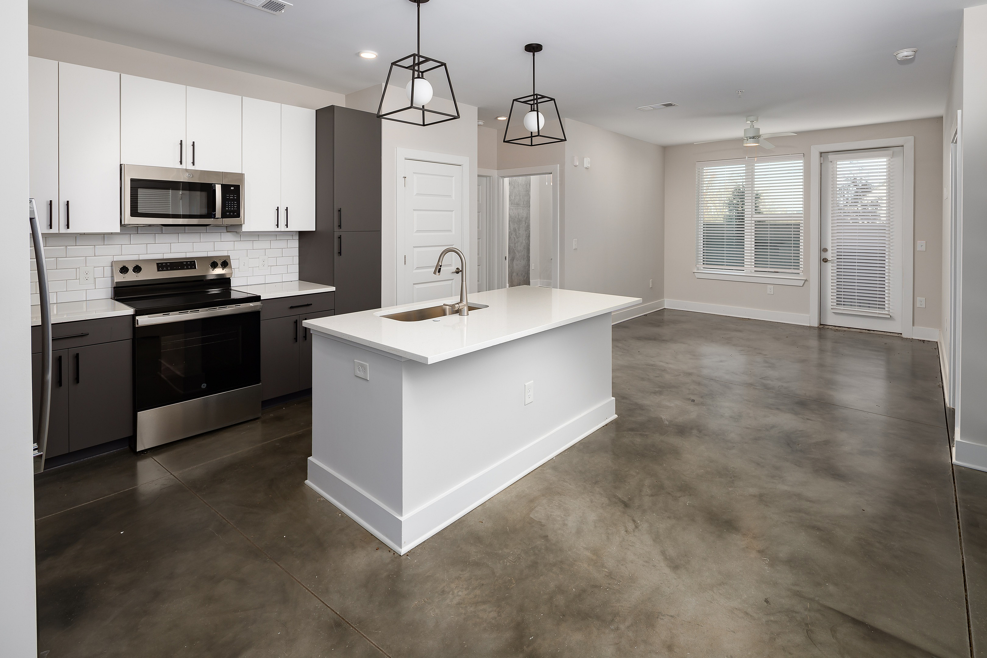 Modern open-concept kitchen and living area with sleek stainless steel appliances, stylish pendant lighting, and large windows for natural light.
