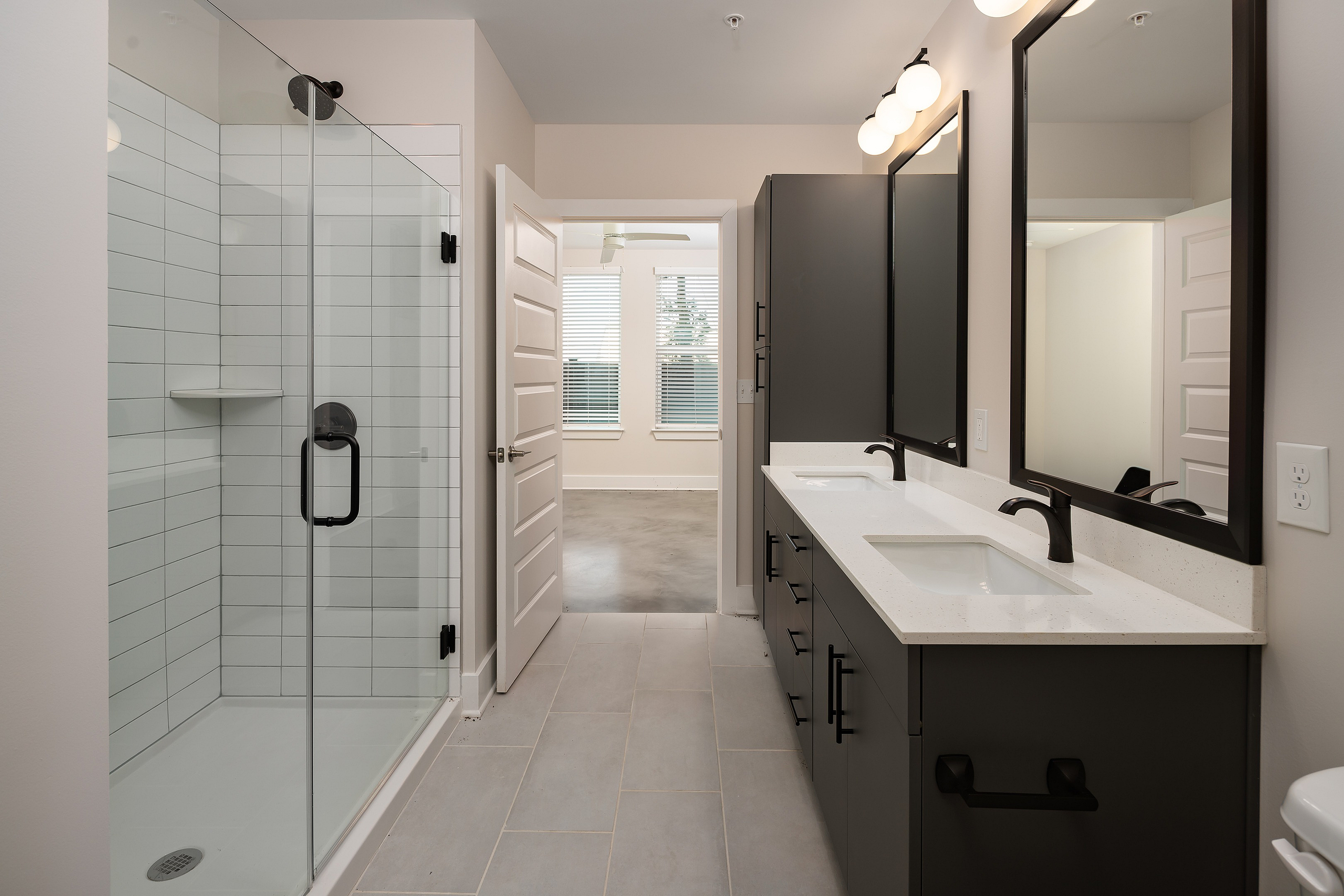 Elegant modern bathroom showcasing double sinks, sleek glass shower, and trendy lighting fixtures.